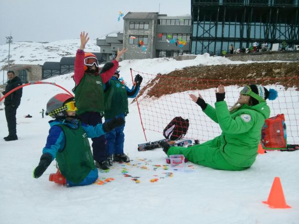 Η εκπαιδεύτρια σκι διασκεδάζει στο βουνό τρεις μικρούς σκιερ με